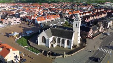 Merkezinde konut evleri, yeşil ağaçlar ve açık mavi bir bahar gününde açık mavi gökyüzü ile çevrili önemli bir kilisenin bulunduğu bir Hollanda kasabasının havadan görünüşü. Huzurlu ve büyüleyici bir atmosfer.