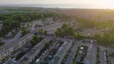 Yuvarlak yolları ve mezar taşlarıyla çevrili, ağaçlarla çevrili ve açık mavi gökyüzünün altındaki yerleşim alanına komşu büyük, düzenli bir mezarlığın havadan görünüşü..