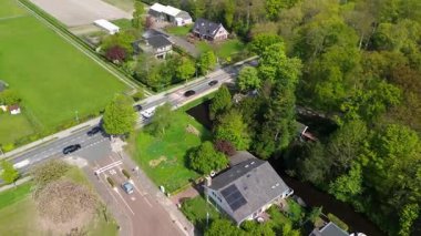 Geniş evleri, yemyeşil bahçeleri, manikürlü çimenleri ve yeşil banliyöde sakin bir yol boyunca uzanan olgun ağaçları olan huzurlu bir yerleşim yeri manzarası..