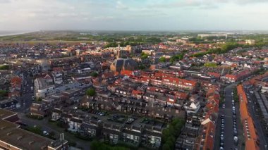 Merkezinde konut evleri, yeşil ağaçlar ve açık mavi bir bahar gününde açık mavi gökyüzü ile çevrili önemli bir kilisenin bulunduğu bir Hollanda kasabasının havadan görünüşü. Huzurlu ve büyüleyici bir atmosfer.