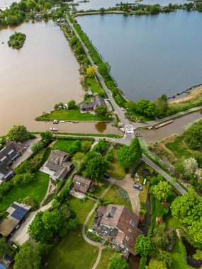 Dar yarımadaları, yeşil tarlaları ve Hollanda kırsalında bulutlu bir gökyüzünün altında sakin sularla çevrili evleri olan manzaralı göl manzaralı bir köy..