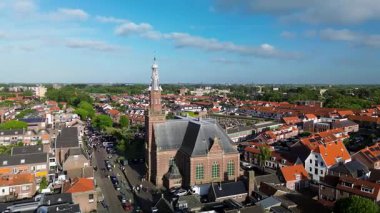 Merkezinde konut evleri, yeşil ağaçlar ve açık mavi bir bahar gününde açık mavi gökyüzü ile çevrili önemli bir kilisenin bulunduğu bir Hollanda kasabasının havadan görünüşü. Huzurlu ve büyüleyici bir atmosfer.