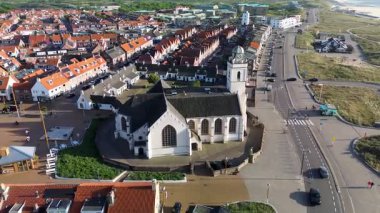 Merkezinde konut evleri, yeşil ağaçlar ve açık mavi bir bahar gününde açık mavi gökyüzü ile çevrili önemli bir kilisenin bulunduğu bir Hollanda kasabasının havadan görünüşü. Huzurlu ve büyüleyici bir atmosfer.