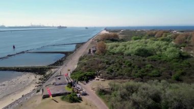 Yeşil su ve kumlu kıyılarla çevrili gelgit havuzları oluşturan bir kıyı dalgası yapısının havadan görünüşü. Dalgalar alçak gelgit sırasında insan yapımı engellere nazikçe dokunur..