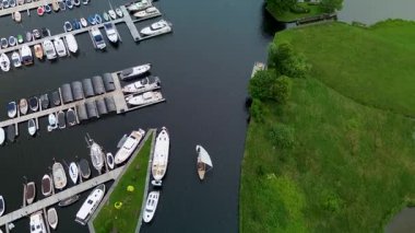 Kanal boyunca beyaz yelkenli bir yat. Güzel bir yel değirmeni. Dar bir kanalın havadan görünüşü yemyeşil çayırlarda akıyor ve küçük bir orman huzur dolu bir marinayla Hollanda köyüne gidiyor.