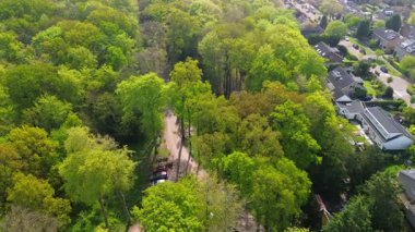 Geniş evleri, yemyeşil bahçeleri, manikürlü çimenleri ve yeşil banliyöde sakin bir yol boyunca uzanan olgun ağaçları olan huzurlu bir yerleşim yeri manzarası..