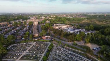 Yuvarlak yolları ve mezar taşlarıyla çevrili, ağaçlarla çevrili ve açık mavi gökyüzünün altındaki yerleşim alanına komşu büyük, düzenli bir mezarlığın havadan görünüşü..