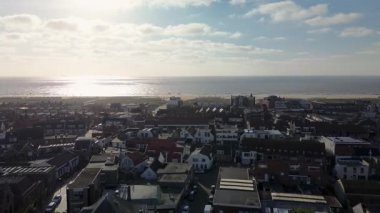 Merkezinde konut evleri, yeşil ağaçlar ve açık mavi bir bahar gününde açık mavi gökyüzü ile çevrili önemli bir kilisenin bulunduğu bir Hollanda kasabasının havadan görünüşü. Arka planda güzel deniz ve sahil.