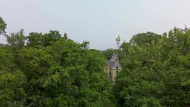 Uçsuz bucaksız yeşil tarlaları, dolambaçlı su yolları ve Hollanda 'nın düz kırsalında parçalı bulutlu bir gökyüzünün altında uzanan bir nehirle çevrili tarihi bir şatonun havadan görünüşü..