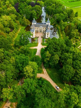Uçsuz bucaksız yeşil tarlaları, dolambaçlı su yolları ve Hollanda 'nın düz kırsalında parçalı bulutlu bir gökyüzünün altında uzanan bir nehirle çevrili tarihi bir şatonun havadan görünüşü..