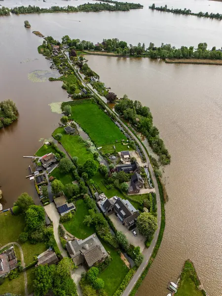 Dar yarımadaları, yeşil tarlaları ve Hollanda kırsalında bulutlu bir gökyüzünün altında sakin sularla çevrili evleri olan manzaralı göl manzaralı bir köy..