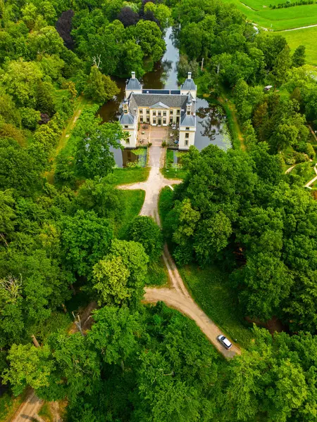 Uçsuz bucaksız yeşil tarlaları, dolambaçlı su yolları ve Hollanda 'nın düz kırsalında parçalı bulutlu bir gökyüzünün altında uzanan bir nehirle çevrili tarihi bir şatonun havadan görünüşü..