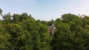 Uçsuz bucaksız yeşil tarlaları, dolambaçlı su yolları ve Hollanda 'nın düz kırsalında parçalı bulutlu bir gökyüzünün altında uzanan bir nehirle çevrili tarihi bir şatonun havadan görünüşü..