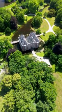 Uçsuz bucaksız yeşil tarlaları, dolambaçlı su yolları ve Hollanda 'nın düz kırsalında parçalı bulutlu bir gökyüzünün altında uzanan bir nehirle çevrili tarihi bir şatonun havadan görünüşü..