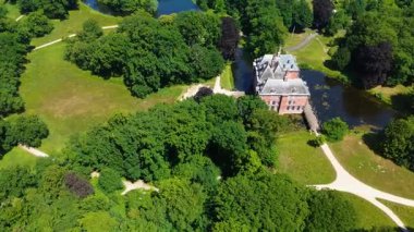 Uçsuz bucaksız yeşil tarlaları, dolambaçlı su yolları ve Hollanda 'nın düz kırsalında parçalı bulutlu bir gökyüzünün altında uzanan bir nehirle çevrili tarihi bir şatonun havadan görünüşü..