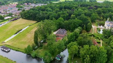 Yoğun bir ormanı, büyük tuğlalı bir evi ve yakınlardaki şatoya benzeyen bir binası olan huzurlu bir kırsal alan. Sakin kanalda dinlenen küçük tekneler ve arka planda sessiz bir köy var..