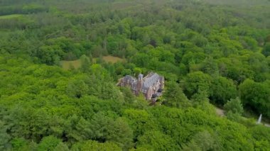 Etrafı yemyeşil ağaçlarla çevrili tarihi bir malikanenin havadan görünüşü ve çeşmesi, yürüyüş yolları ve park yeri olan güzel manzaralı bir bahçe. Sahne canlı yaz yeşilliklerini gösteriyor..