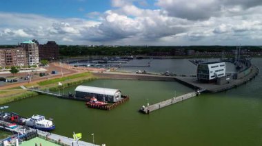 Virajlı rıhtımlar boyunca kenetlenmiş yatları olan modern bir marinanın havadan görünüşü. Limanın çevresinde yerleşim yerleri var.