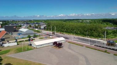 Lelystad, Flevoland, Hollanda - 09.06.2025: Liman, renkli binalar, yüksek bir iletişim kulesi olan kıyı kasabasının havadan görünüşü. Çevredeki alanlar arasında park alanları ve yeşil alanlar yer alıyor.