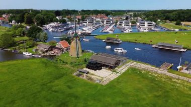 Kanal boyunca beyaz yelkenli bir yat. Güzel bir yel değirmeni. Dar bir kanalın havadan görünüşü yemyeşil çayırlarda akıyor ve küçük bir orman huzur dolu bir marinayla Hollanda köyüne gidiyor.