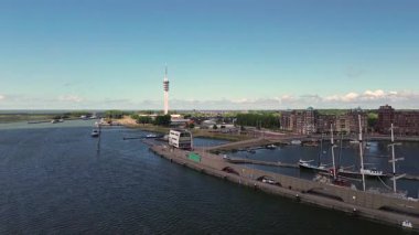 Lelystad, Flevoland, Hollanda - 09.06.2025: Liman, renkli binalar, yüksek bir iletişim kulesi olan kıyı kasabasının havadan görünüşü. Çevredeki alanlar arasında park alanları ve yeşil alanlar yer alıyor.