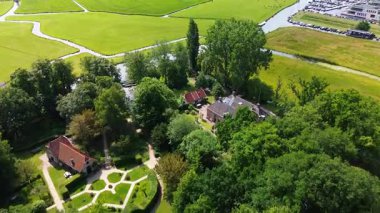 Yoğun bir ormanı, büyük tuğlalı bir evi ve yakınlardaki şatoya benzeyen bir binası olan huzurlu bir kırsal alan. Sakin kanalda dinlenen küçük tekneler ve arka planda sessiz bir köy var..