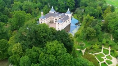 Uçsuz bucaksız yeşil tarlaları, dolambaçlı su yolları ve Hollanda 'nın düz kırsalında parçalı bulutlu bir gökyüzünün altında uzanan bir nehirle çevrili tarihi bir şatonun havadan görünüşü..