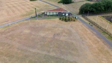 Rotterdam, Güney Hollanda, Hollanda - 09.06.2025: Sahile yakın bir binanın havadan görünüşü, çimlerle çevrili bir yol, park etmiş arabaların olduğu bir yol ve kıyı şeridine giden yürüyüş yolları.