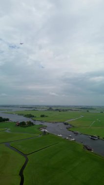 Yüzen evler ve yeşil tarlalarla kaplı huzurlu bir nehirde küçük tekneler dolaşır. Hava görüntüsü sakin suyu, canlı manzarayı ve sakin kırsal atmosferi yakalar..