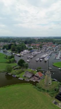 Kanal boyunca beyaz yelkenli bir yat. Güzel bir yel değirmeni. Dar kanalın havadan görünüşü yemyeşil çayırlarda ve küçük bir ormanda akıyor.