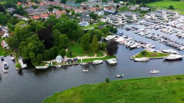 Kanal boyunca beyaz yelkenli bir yat. Güzel bir yel değirmeni. Dar kanalın havadan görünüşü yemyeşil çayırlarda ve küçük bir ormanda akıyor.