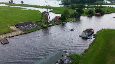 Yüzen evler ve yeşil tarlalarla kaplı huzurlu bir nehirde küçük bir tekne geziniyor. Hava görüntüsü sakin suyu, canlı manzarayı ve sakin kırsal atmosferi yakalar..