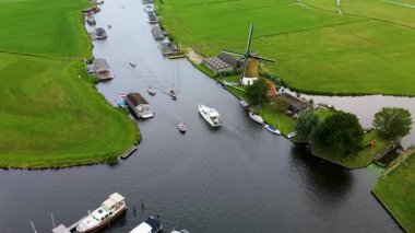 Yüzen evler ve yeşil tarlalarla kaplı huzurlu bir nehirde küçük bir tekne geziniyor. Hava görüntüsü sakin suyu, canlı manzarayı ve sakin kırsal atmosferi yakalar..