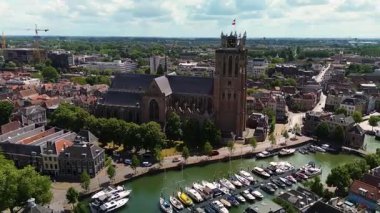 Deniz kenarındaki tarihi bir saat kulesinin büyüleyici hava manzarası. Etrafı büyüleyici Hollandalı evler, tekneler ve kanallarla çevrili. Sahne, eski Avrupa mimarisinin ve liman yaşamının güzelliğini yansıtıyor..