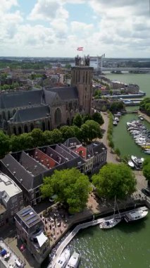 Deniz kenarındaki tarihi bir saat kulesinin büyüleyici hava manzarası. Etrafı büyüleyici Hollandalı evler, tekneler ve kanallarla çevrili. Sahne, eski Avrupa mimarisinin ve liman yaşamının güzelliğini yansıtıyor..