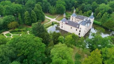 Uçsuz bucaksız yeşil tarlaları, dolambaçlı su yolları ve Hollanda 'nın düz kırsalında parçalı bulutlu bir gökyüzünün altında uzanan bir nehirle çevrili tarihi bir şatonun havadan görünüşü..