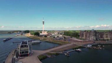 Lelystad, Flevoland, Hollanda - 09.06.2025: Liman, renkli binalar, yüksek bir iletişim kulesi olan kıyı kasabasının havadan görünüşü. Çevredeki alanlar arasında park alanları ve yeşil alanlar yer alıyor.