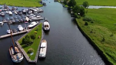 Kanal boyunca beyaz yelkenli bir yat. Güzel bir yel değirmeni. Dar kanalın yemyeşil alanlar boyunca uzanan havadan görünüşü. Huzurlu bir nehirde giden küçük bir tekne.