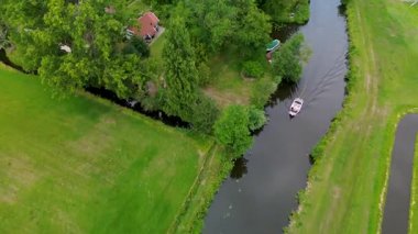 Kumlu bir sahilin havadan görünüşü. İnsanlar sığ gel-git havuzları ve kum havuzlarının yanında yürüyor. Denizden hafif dalgalar yaklaşıyor..