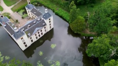 Kumlu bir sahilin havadan görünüşü. İnsanlar sığ gel-git havuzları ve kum havuzlarının yanında yürüyor. Denizden hafif dalgalar yaklaşıyor..