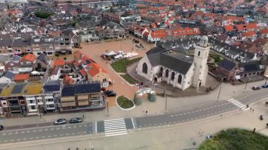 Katwijk aan Zee, Güney Hollanda, Hollanda - 09.06.2025: Kırmızı çatılı evleri, merkezi bir kilisesi ve geometrik bahçesi olan bir Avrupa kıyı kasabasının havadan görünüşü. Arabalarla dolu geniş bir yol.