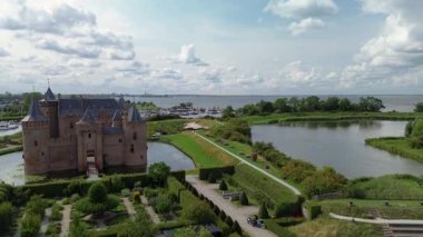 Hollanda 'daki Muiderslot Kalesi' nin göz kamaştırıcı hava manzarası, kanallarla çevrili, tekne dolu bir marina ve ufka doğru uzanan büyüleyici bir kasaba manzarası..