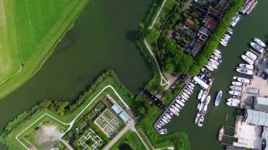 Muiden, Kuzey Hollanda, Hollanda - 09.06.2025 Birçok yelkenli ve yatı kenetlenmiş bir marinanın havadan görünüşü, geniş bir göle veya denize açılan bir kanal, ve yemyeşil, parçalı bulutlu bir gökyüzü.