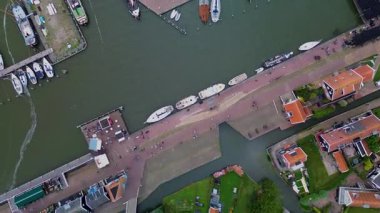 Yelkenli bir Hollanda limanının havadan görünüşü, kırmızı çatılı geleneksel siyah ahşap evler, ve manzaralı bir köyde rıhtım geçidi..