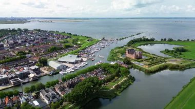 Muiden, Kuzey Hollanda, Hollanda - 09.06.2025: Hollanda 'daki Muiderslot Kalesi' nin büyüleyici hava manzarası, kanallarla çevrili, tekne dolu bir yat limanı ve genişleyen büyüleyici bir kasaba manzarası