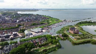 Muiden, Kuzey Hollanda, Hollanda - 09.06.2025: Hollanda 'daki Muiderslot Kalesi' nin büyüleyici hava manzarası, kanallarla çevrili, tekne dolu bir yat limanı ve genişleyen büyüleyici bir kasaba manzarası