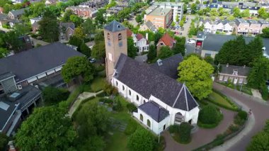 Avrupa 'nın küçük bir kasabasındaki ağaçlar, evler ve caddelerle çevrili yüksek tuğlalı tarihi bir kilise manzarası..