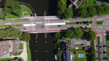 Utrecht, Utrecht bölgesi, Hollanda - 09.06.2025: Nehir, sanayi binaları, tekneler ve yerleşim alanları ile modern bir şehir manzarası. Köprüsü olan işlek bir yol denizi geçer.