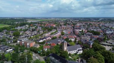Kırmızı çatıları, yeşil ağaçları ve tarlalarıyla çevrili tarihi binaları olan büyüleyici bir Avrupa kasabasının havadan görünüşü doğa ve mimarinin barışçıl bir karışımını sergiliyor..
