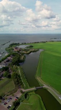 Muiden, Kuzey Hollanda, Hollanda - 09.06.2025: Hollanda 'daki Muiderslot Kalesi' nin büyüleyici hava manzarası, kanallarla çevrili, tekne dolu bir yat limanı ve genişleyen büyüleyici bir kasaba manzarası